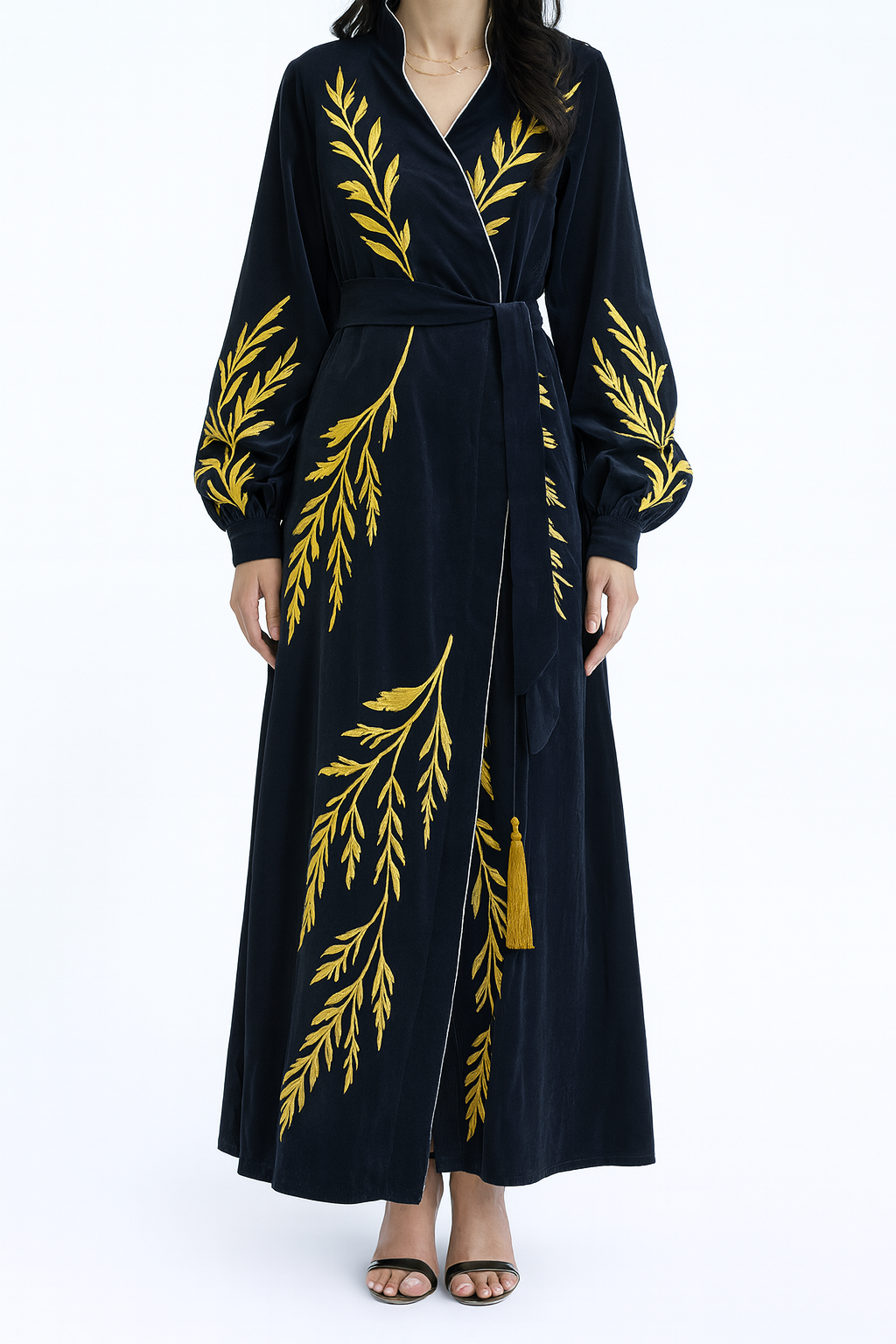 Black dress with gold leaf patterns worn by a model on a white background